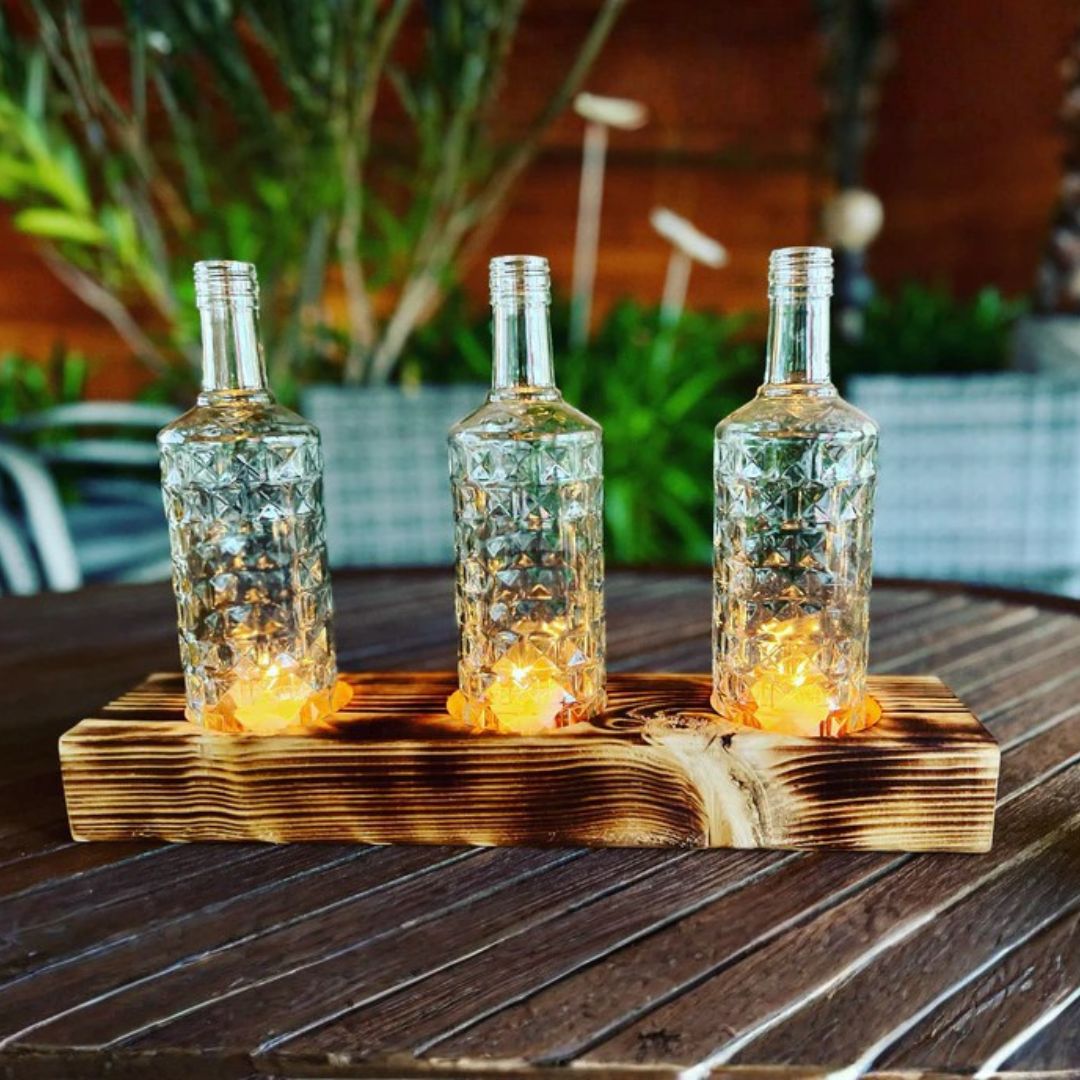 Triple candle holder made from recycled bottles with a wooden base