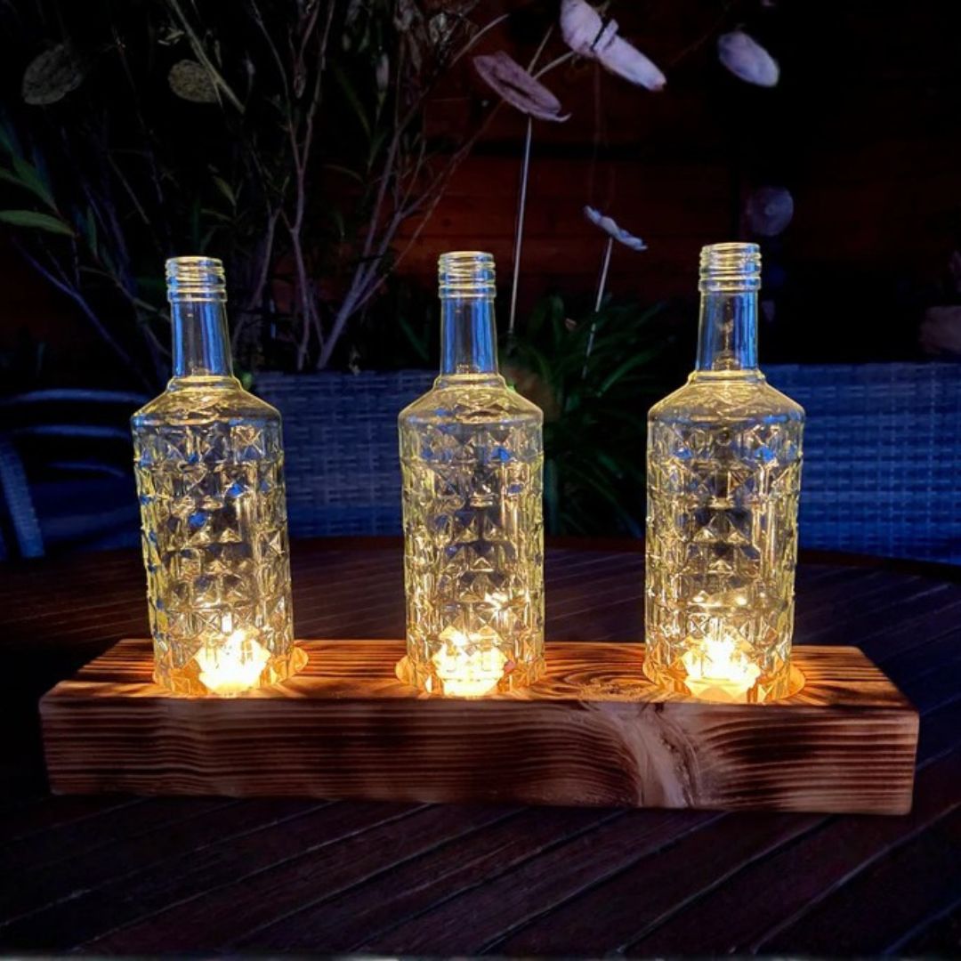 Triple candle holder made from recycled bottles with a wooden base